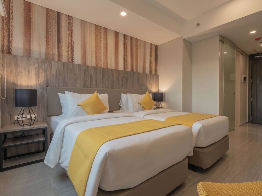 A hotel room with two beds, a large window, and a wooden headboard.