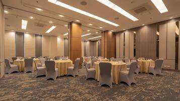 A conference room with multiple round tables, chairs, and a carpeted floor.
