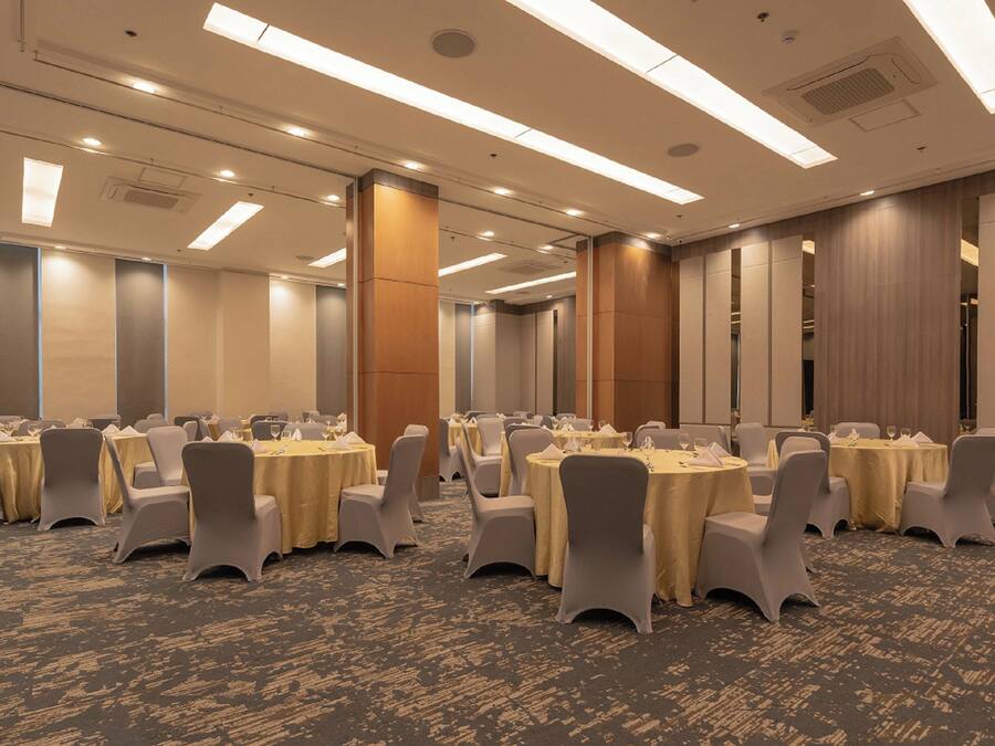 A conference room with multiple round tables, chairs, and a carpeted floor.