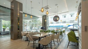 A modern cafe with wicker chairs, tables, and pendant lighting.