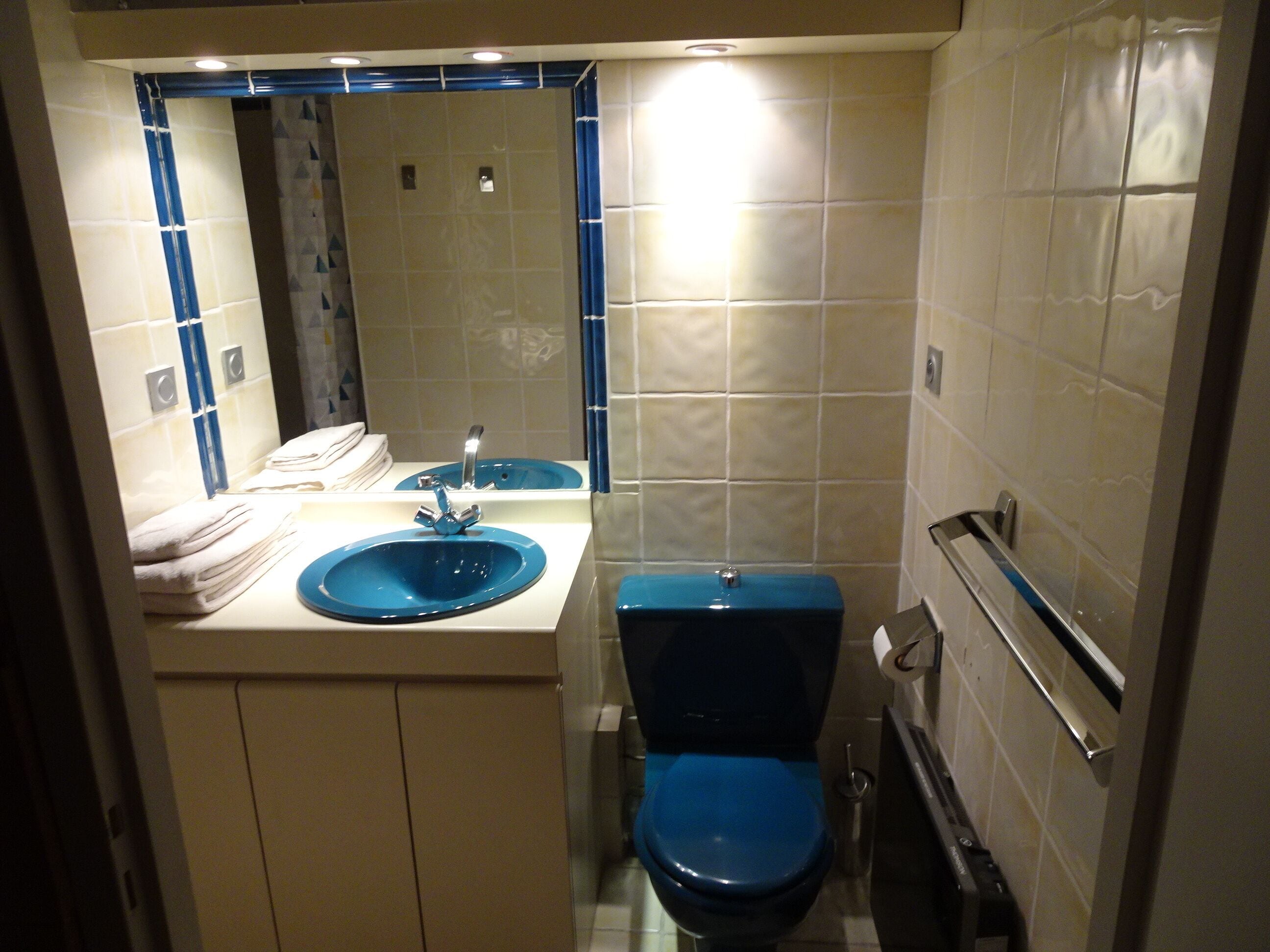 A bathroom with a blue sink, a toilet, and a mirror above the sink.