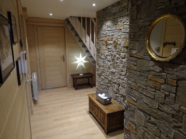 A hallway with a wooden floor, a stone wall, a wooden bench with a star-shaped light, and a mirror on the wall.