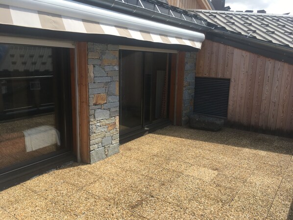 A building with a stone facade, large glass doors, and a gravel-covered ground.
