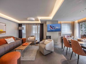 A modern living room with a sofa, armchairs, a coffee table, and a dining area with chairs and a table. - Modern apartment with fireplace, parking and Wi-Fi, Courchevel (Courchevel 1650)