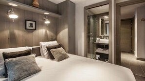 Une chambre moderne avec un grand lit, une tête de lit en bois et une cabine de douche en verre.