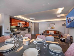 A modern living room with a dining area set for a meal.
