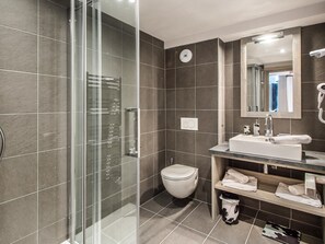 A modern bathroom with a glass shower enclosure, a white toilet, a sink with a mirror, and a towel rack.