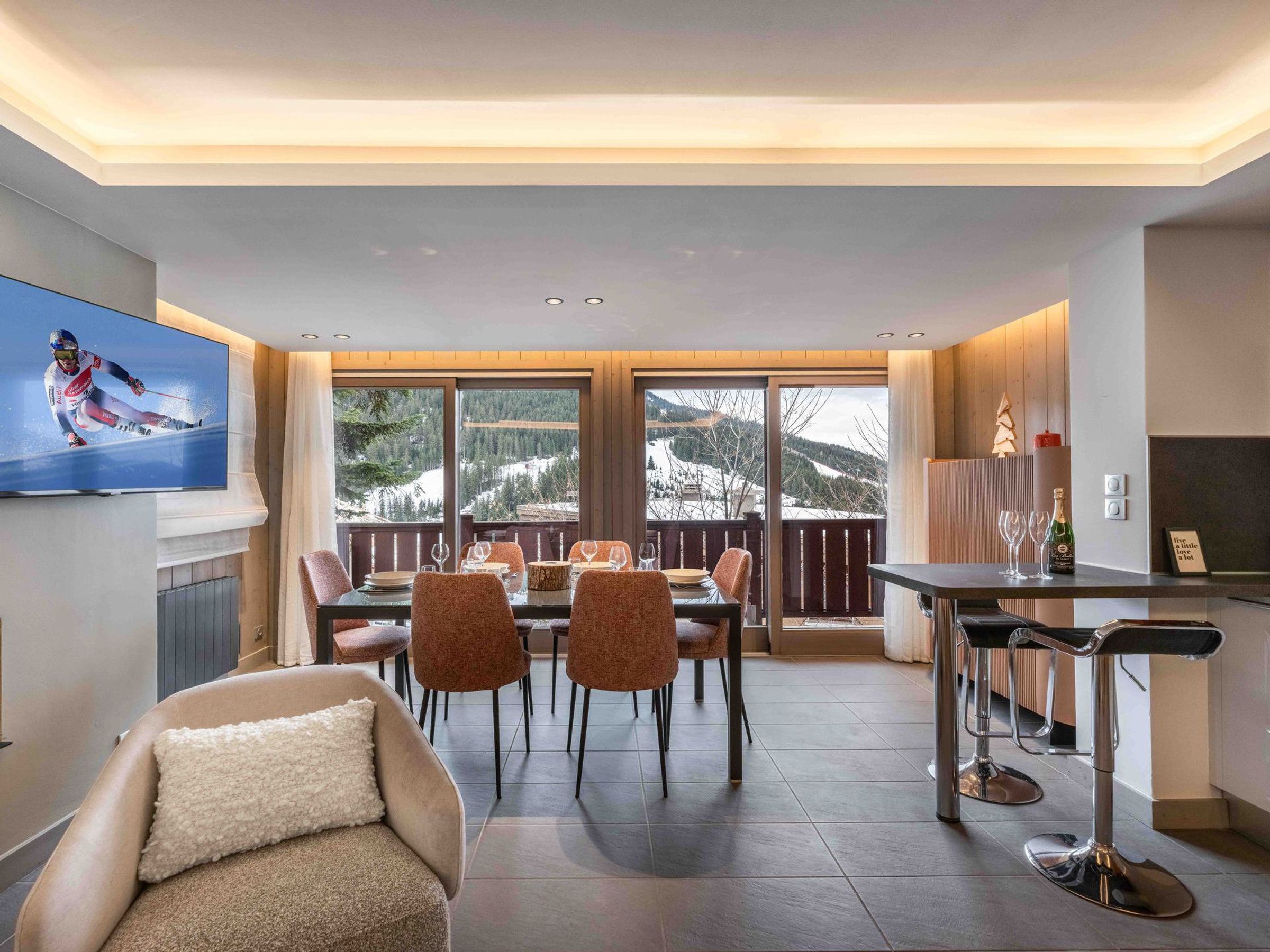 A modern dining area with a large window view of a snowy mountain landscape.
