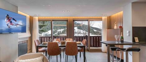 A modern dining area with a large window view of a snowy mountain landscape.