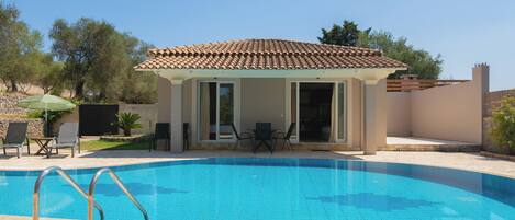Una piscina al aire libre, sillones reclinables de piscina