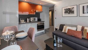 A modern kitchen with a dining area, a sofa, and two framed pictures on the wall. - Cozy apartment in Courchevel with spacious bedroom and parking (Courchevel 1650)