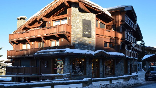A multi-story lodge with stone and wood construction, featuring balconies and large windows.