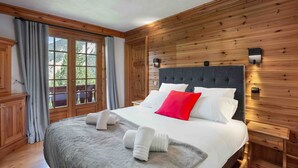 A bedroom with a large bed, wooden paneling, a window with curtains, and a nightstand. - Charming Savoyard chalet, sleeps 12, sauna, piste access, Moriond (Courchevel 1650)