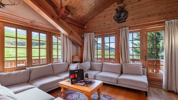A cozy room with a wooden ceiling, large windows, and a sofa set. - Charming Savoyard chalet, sleeps 12, sauna, piste access, Moriond (Courchevel 1650)