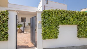 Un bâtiment moderne à l’extérieur blanc, doté d’une entrée sécurisée et d’une haie bien entretenue.