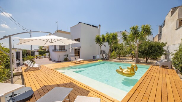 Piscina com deck de madeira, espreguiçadeiras e guarda-sóis.