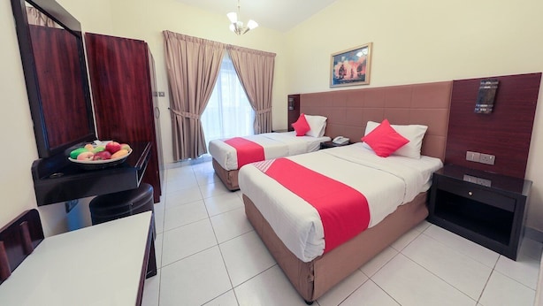 Habitación de hotel con dos camas, una mesa de comedor con fruta, un televisor y un cuadro en la pared.