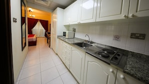Una cocina con armarios blancos, microondas, lavabo y estufa.
