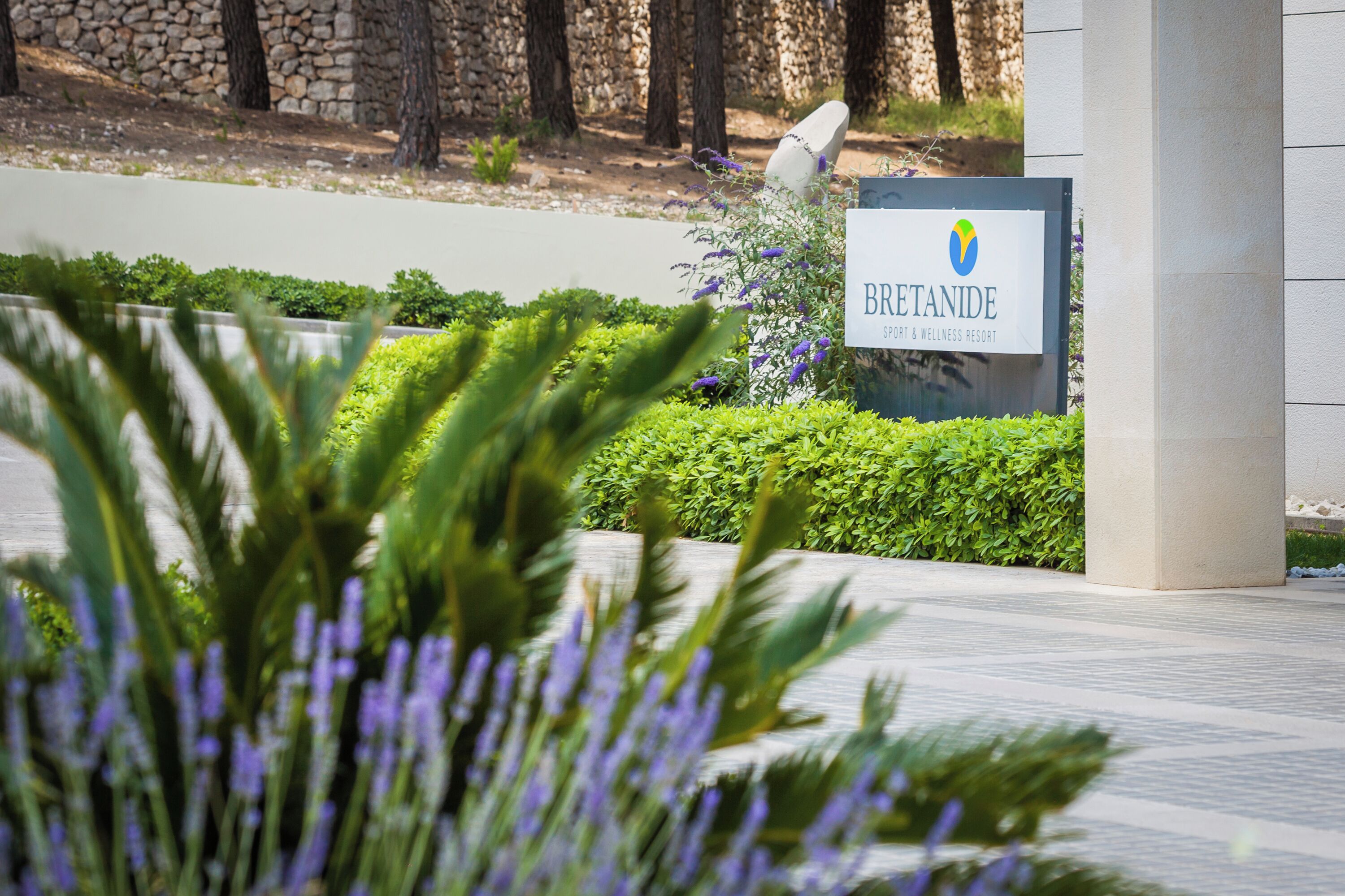 A sign for Bretanide Spa & Wellness Resort with a stone wall and greenery in the background.