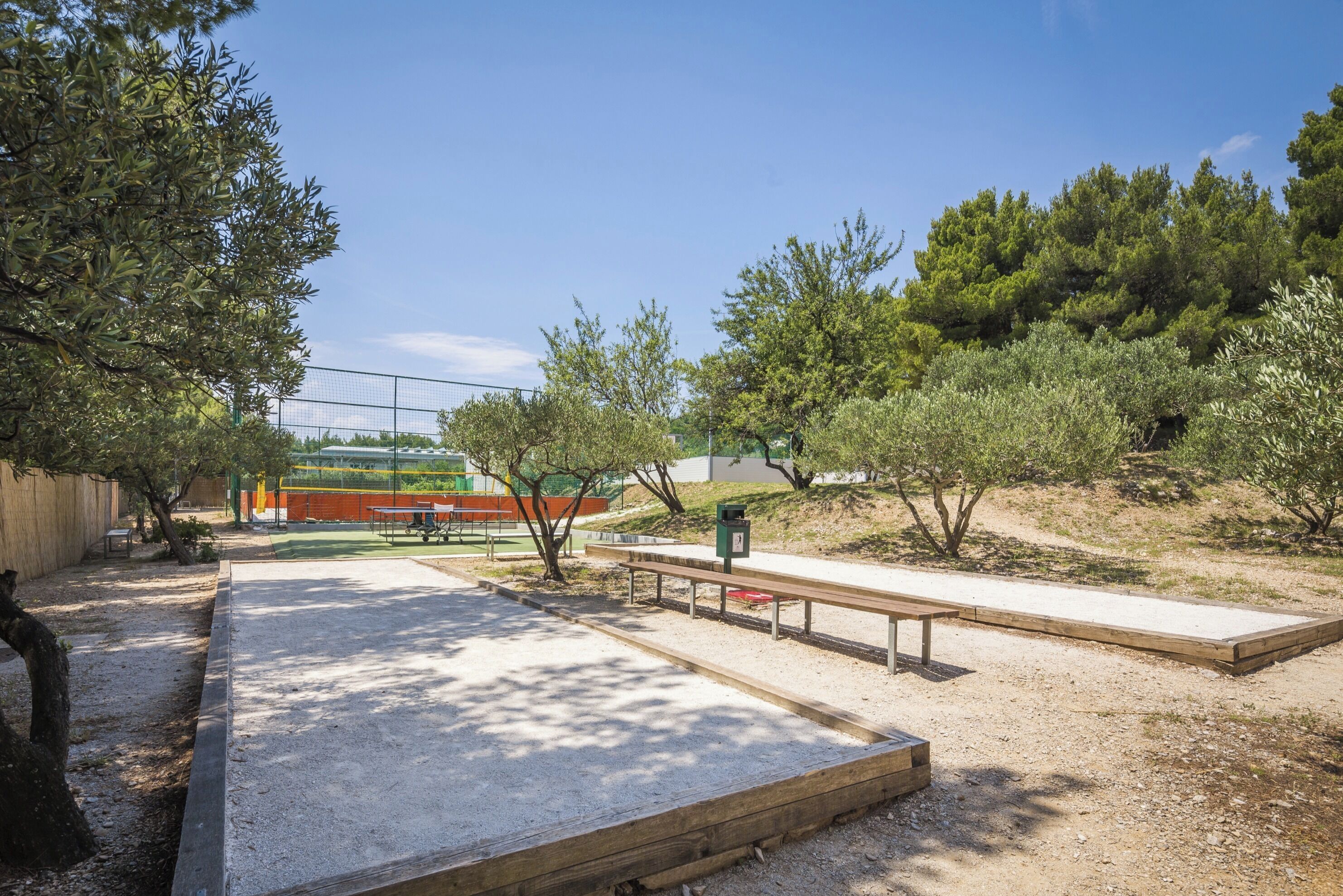 An outdoor area with a concrete play area, benches, and trees.