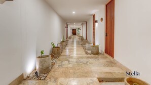 A hallway with a tiled floor, potted plants, and wooden doors. - Tulum Jungle Condo with Private Terrace & Jacuzzi (Tulum)
