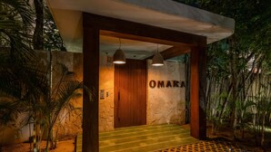 A modern building entrance with a wooden door and the name "OMARA" on the wall. - Tulum Jungle Condo with Private Terrace & Jacuzzi (Tulum)