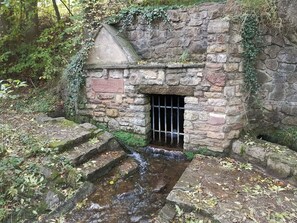 Una estructura de piedra con una cascada pequeña y escalones que la ascienden.