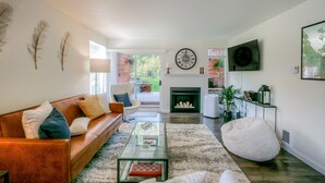 A modern living room with a leather sofa, glass coffee table, and a fireplace.