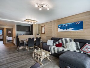 A modern living room with a sofa, a glass coffee table, and a dining area with chairs and a table.