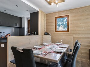 A modern dining area with a wooden partition, a table set for four, and a view of a mountainous landscape through a window.