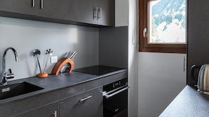Een moderne keuken met donkere kastjes, een roestvrijstalen spoelbak en een raam met uitzicht op de bergen.
