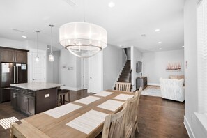 Enjoy meals in the central dining area with a wooden table and chairs, surrounded by ample natural light.