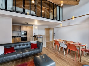 Un apartamento moderno estilo loft con comedor, cocina y un sofá de cuero negro con cojines rojos.