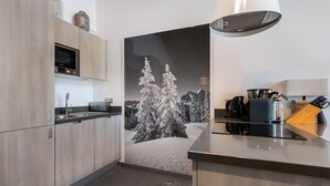 Moderni keittiö, jossa on puiset kaapit, sisäänrakennettu mikroaaltouuni ja kahvinkeitin.