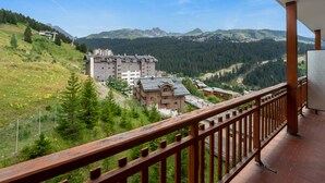 A hotel with multiple buildings, a balcony with a wooden railing, and a mountainous landscape in the background.