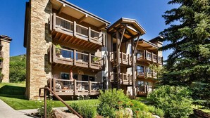 A multi-story building with balconies, stone facade, and a well-maintained garden. - Access to Snowmass Mtn Via Trail! Balcony W/ Stunning Views, Pool/Hot Tub, Loft, Wood FP & Parking (Snowmass Village)