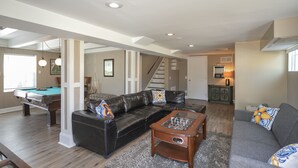 A spacious living room with a pool table, a leather sofa, and a coffee table. - Dog-Friendly Shelby Park Home · 3BR Sleeps 8 (Nashville)