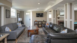 A living room with a grey sofa, a black leather sofa, a wooden coffee table, and a fireplace. - Dog-Friendly Shelby Park Home · 3BR Sleeps 8 (Nashville)