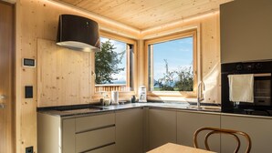 Una cocina moderna con armarios de madera, estufa empotrada y un ventanal con vistas al exterior.