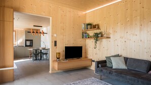 Una sala moderna con pared de madera, un televisor de pantalla plana, un sofá y un comedor con sillas y una mesa.