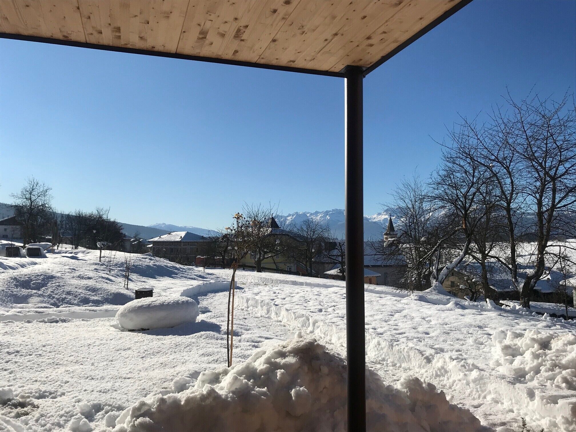 A snowy landscape with buildings, a clear sky, and mountains in the background.
