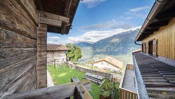 A wooden building with a view of mountains and a grassy area with benches.