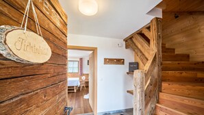 A wooden interior with a sign reading 'Tichthuhill,' a staircase, and a hallway leading to a room with a bed and a window. - Holiday Home “Fichtnhittl” with Mountain View, Wi-Fi, Balcony, Terrace & Garden (Algund)