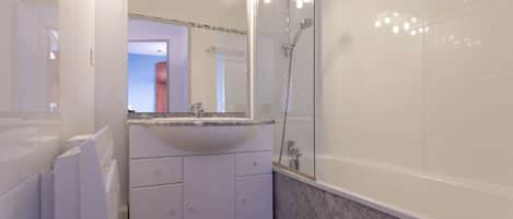 A bathroom with a white sink, mirror, and shower.