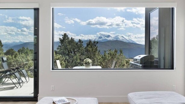 Een slaapkamer met een groot raam en uitzicht op bergen.