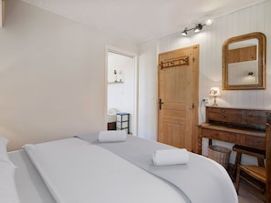 A bedroom with a bed, a wooden dresser, a mirror, and a door. - Apartment for 6 in Courchevel 1650 center, direct access to slopes (Courchevel 1650)