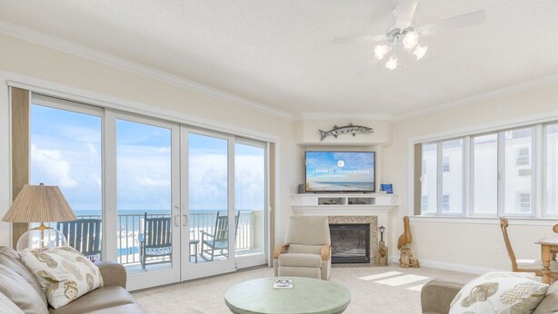 A spacious living room with a large window, a fireplace, and a television on the wall.