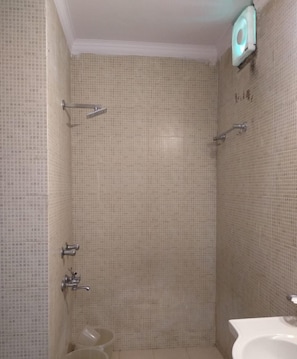 A bathroom with a tiled shower wall, a toilet, and a sink.