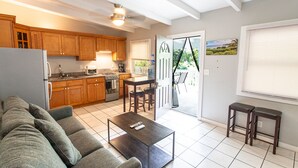 A modern kitchen with wooden cabinets, a dining area, and a living room with a sofa and coffee table. - Walk to Cane Bay Beach Cottage - End Unit with Mountain Views (Christiansted)