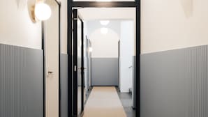 Un couloir doté d’un sol recouvert de moquette, de murs blancs et gris et d’un chambranle de porte noir.